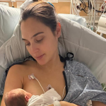 Gal Gadot sitting in a hospital bed holding her newborn baby, showing relief and gratitude.