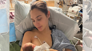 Gal Gadot sitting in a hospital bed holding her newborn baby, showing relief and gratitude.